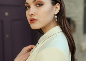 a woman in a white jacket and earrings