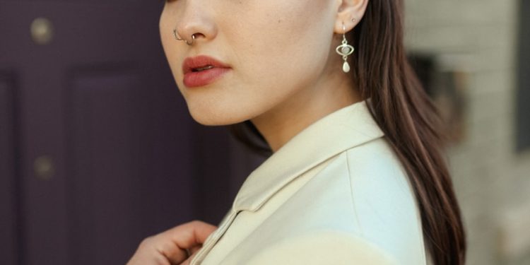 a woman in a white jacket and earrings
