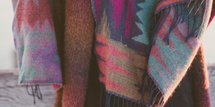 woman wearing brown knitted cardigan standing beside fence
