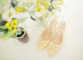 pair of women's beige pointed-toe slingback pumps with ribbons near flower vase