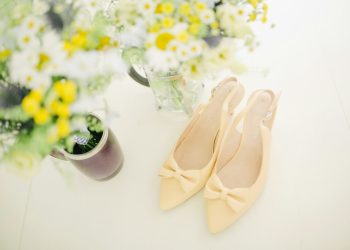 pair of women's beige pointed-toe slingback pumps with ribbons near flower vase