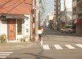 a woman walking down a street next to a traffic light