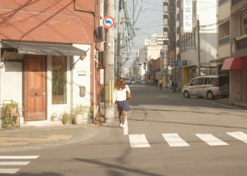 a woman walking down a street next to a traffic light