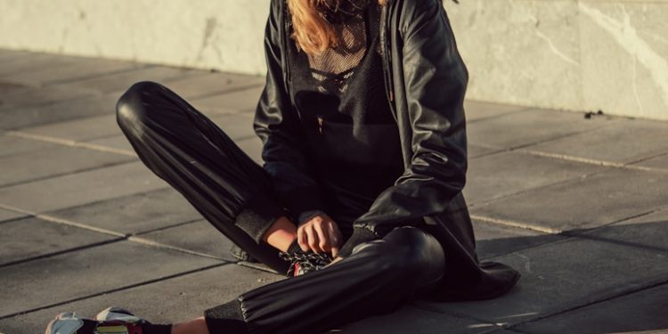 woman in black leather jacket and black pants sitting on floor